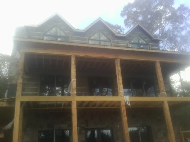 Dormers and porch framing on a large log home under construction — Roof Coating work by our crew in Newtonville