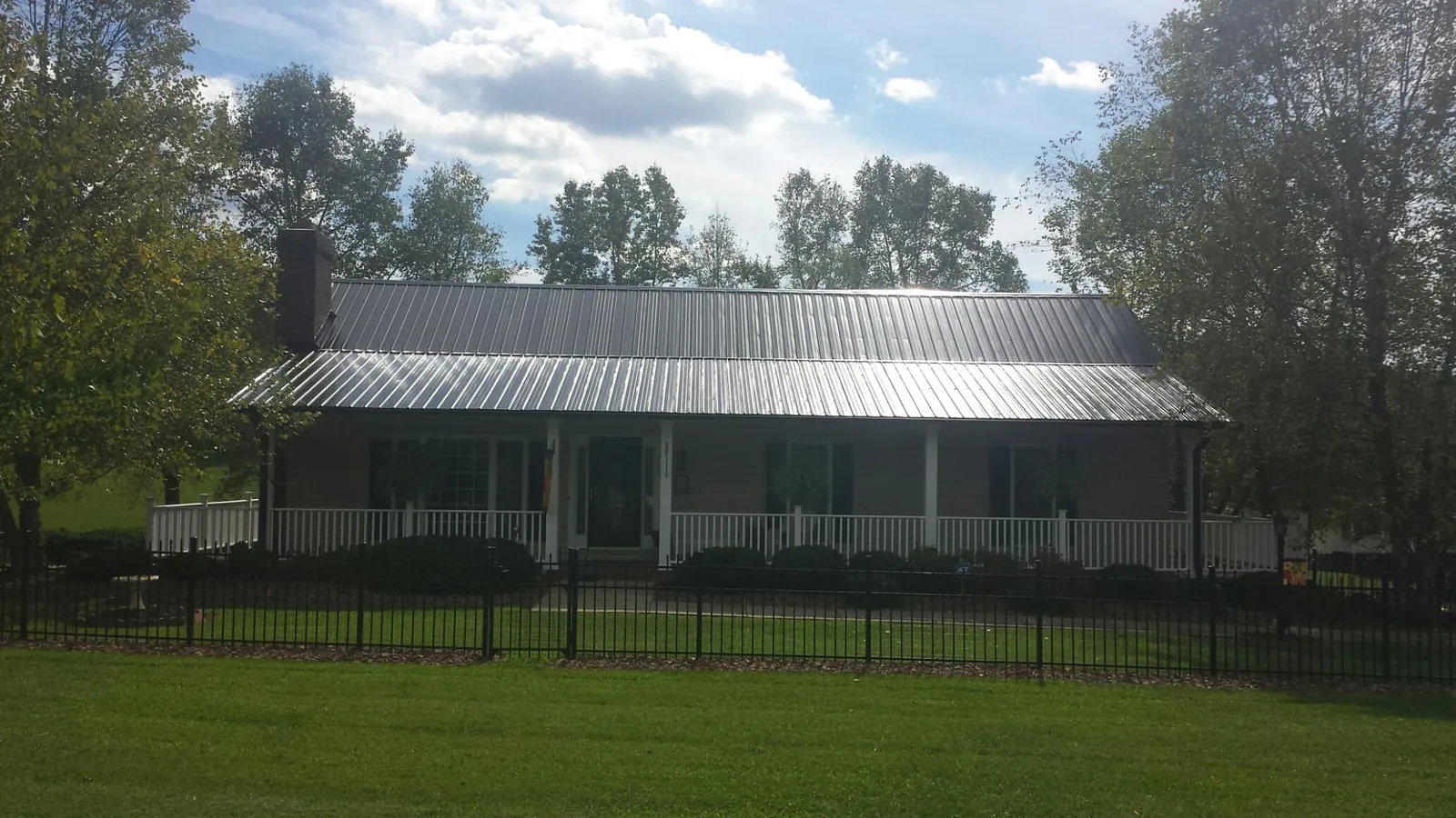 Gray metal roof on a brick ranch with a full width front porch — Gutter Guard Installation work by our crew in Newtonville